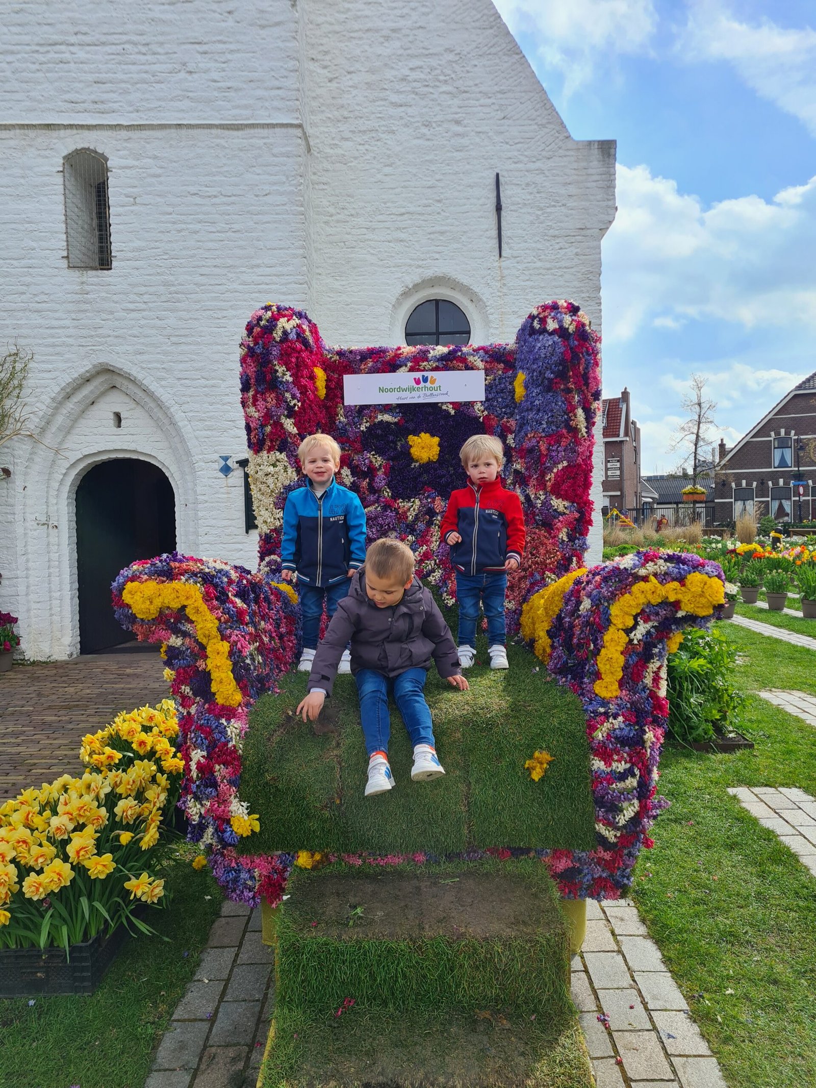 Three boys on the giant hyacinth flower throne next to the Witte Kerk in Noordwijkerhout 2023